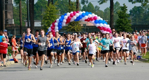 Runners running toward the camera with balloon arch in background